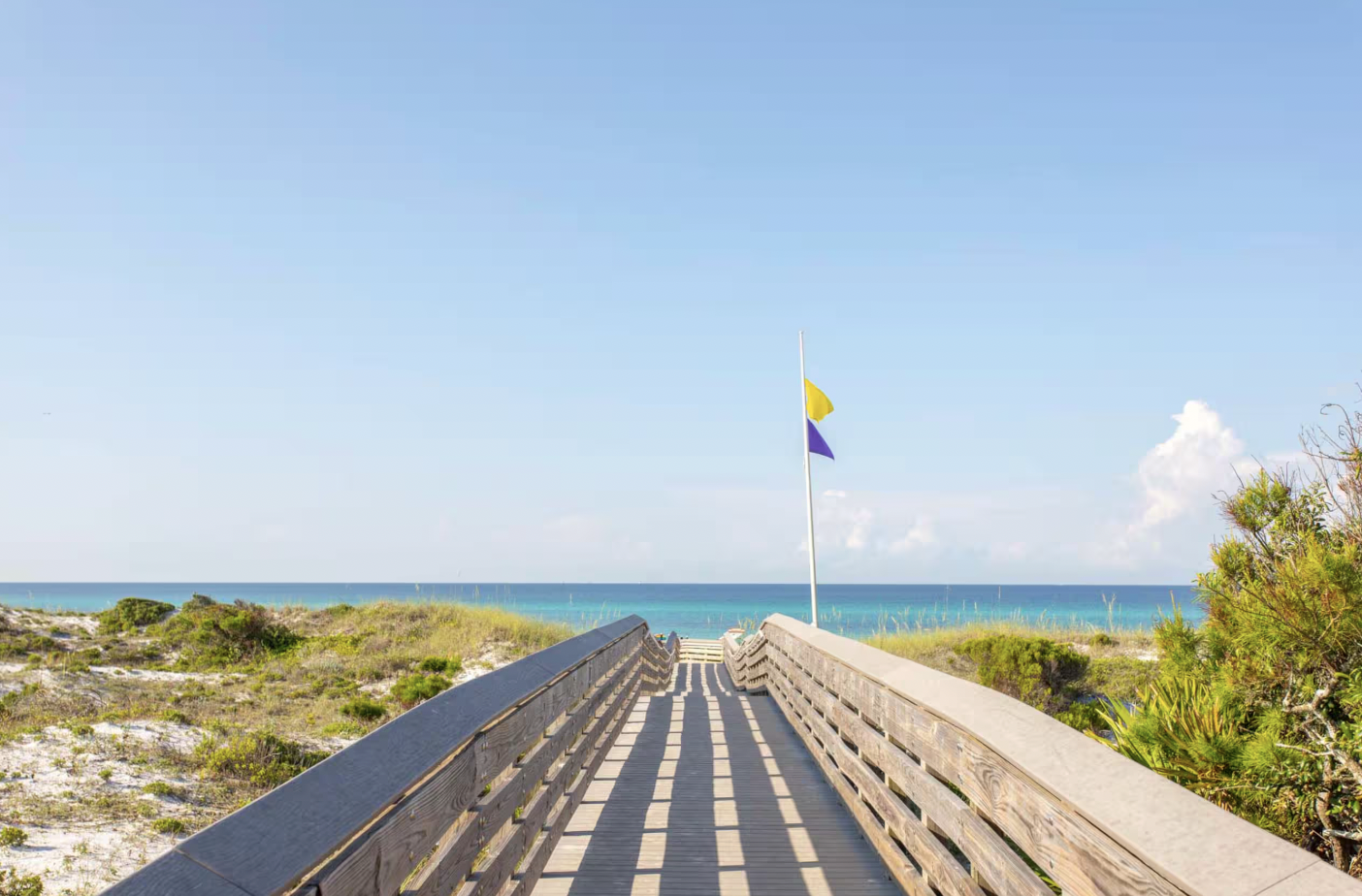 Wooden beach boardwalk over dunes to emerald Gulf water